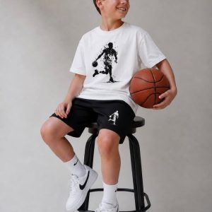 Σετ αγοριού με λευκή κοντομάνικη μπλούζα με τύπωμα μπασκετμπολίστα και μαύρη αθλητική βερμούδα.